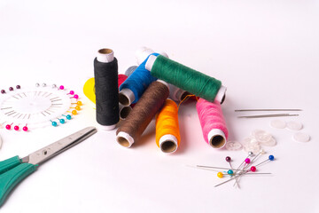 Colorful sewing thread set and needles isolated on background.