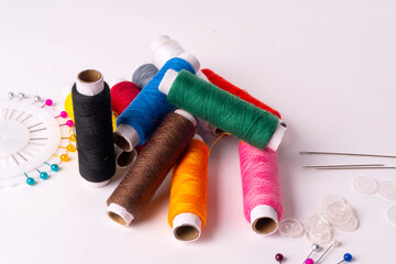 Colorful sewing thread set and needles isolated on background.