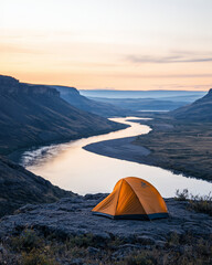 Obraz premium A solitary campsite on rocky outcrop offers breathtaking views of winding river at sunset. vibrant orange tent contrasts beautifully with serene landscape, evoking sense of adventure and tranquility