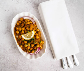 Traditional chickpea dish served in an elegant white dish. The dish is garnished with a lemon...