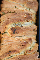 Loaf of freshly baked pull apart bread with garlic and rosemary in metal pans