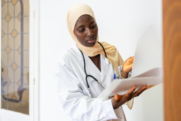 Black female doctor in hijab reviewing medical records