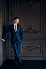 portrait of groom in blue three piece suit with tie on wedding day