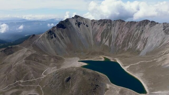 Backward ascending flight over Laguna del Sol at Nevado de Toluca volcano reveals high-altitude aerial panorama. Mexico