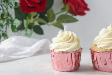 cupcakes in pink foil liners with vanilla buttercream, frosted cupcakes on a white background