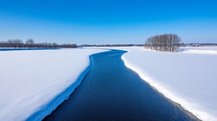 Calm winter river flowing through snow-covered banks with empty space over the clear blue sky for text 
