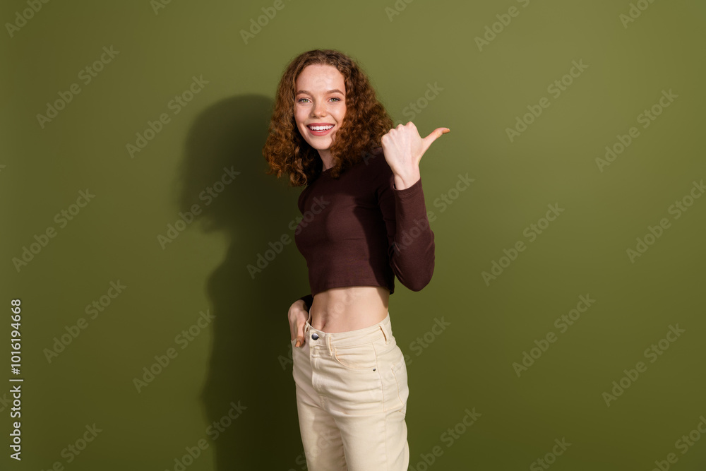 Wall mural Photo of shiny attractive young lady dressed brown outfit showing thumb back empty space isolated khaki color background