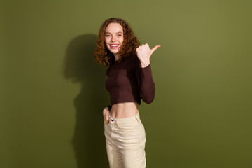 Photo of shiny attractive young lady dressed brown outfit showing thumb back empty space isolated khaki color background