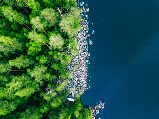 Aerial view of blue water lake with stone coast and green summer woods in Finland