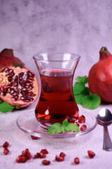 Turkish pomegranate tea in a glass glass and fresh pomegranate. Fresh mint and pomegranate seeds on the surface.