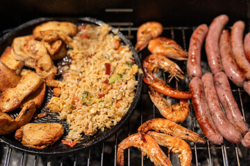 A grill with a variety of food including chicken fried rice shrimp and sausages