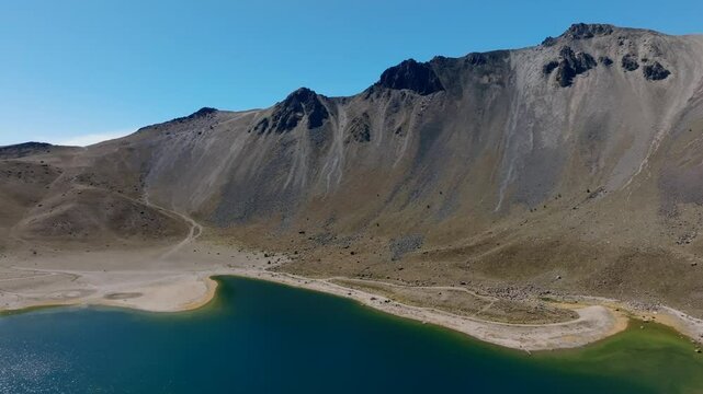 Nevado de Toluca peak and Laguna del Sol, glacial lake inside volcano crater. Mexico. Aerial drone, pan left