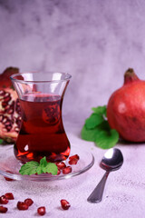Turkish pomegranate tea in a glass glass and fresh pomegranate. Fresh mint and pomegranate seeds on the surface.