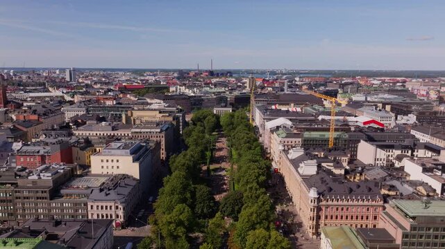 Aerial views highlight Helsinki city center, showcasing the beautiful esplanadi park and impressive architecture. The scene captures a lively urban landscape beneath a clear blue sky