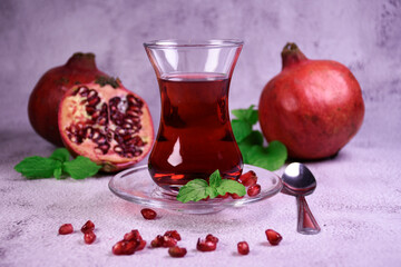 Turkish pomegranate tea in a glass glass and fresh pomegranate. Fresh mint and pomegranate seeds on the surface.