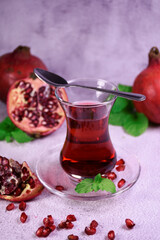 Turkish pomegranate tea in a glass glass and fresh pomegranate. Fresh mint and pomegranate seeds on the surface.