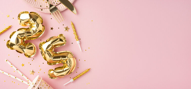 Gold number balloons and birthday decorations on a pink background, creating a festive and celebratory atmosphere