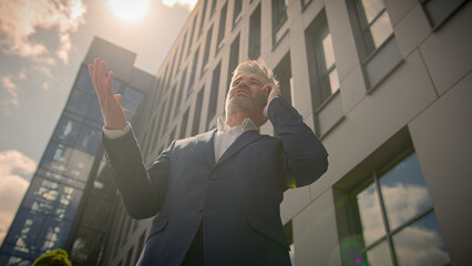 Bottom view succeed senior businessman mature middle-age investor city building developer real estate trader realtor business man entrepreneur talking mobile phone call outdoors pointing with hands
