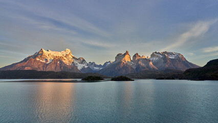 the Cuernos del Paine and Cerro Paine Grande at sunrise in Torres del Paine National Park, Chile, with the golden sunlight reflecting off Lago Pehoé.