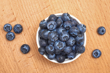 Bowl of ripe blueberries on wooden table. Top view. Healthy eating