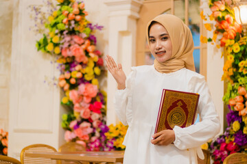 young girl veil wearing a white dress muslim cheerful to the camera hand holding a book, the quran while presenting in a luxurious interior. for fashion content, promotion, lifestyle, religion