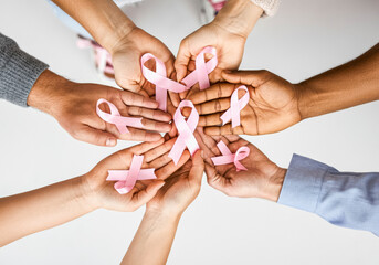 Diverse hands holding pink ribbons in support of breast cancer awareness