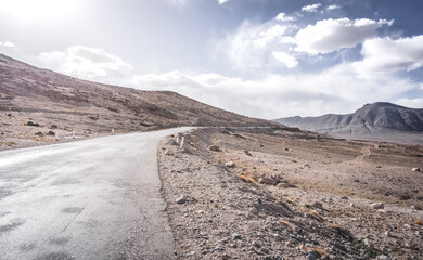 The asphalt road of the Pamir Highway winds and twists in the valley of the Tien Shan mountains in Tajikistan in Pamir, landscape in the high desert mountains for the background