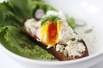 Poached Egg with Black Pepper on Toasted Bread with Cream Cheese and Pumpkin Seeds. Healthy Breakfast.