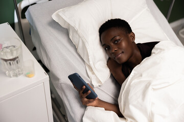 Deep in thought, the young African woman stares at her phone, completely engrossed in its contents.