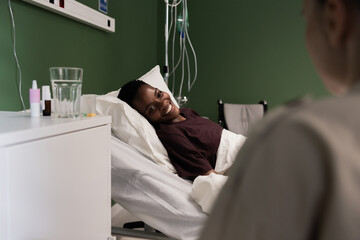 African patient receives care in the hospital, supported by her friend.