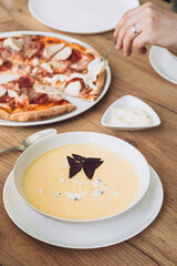 Cheese cream soup and pizza in the home kitchen, homemade food for family lunch.