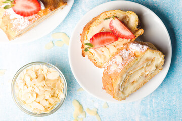 Sliced rolls with custard. The dessert is decorated with fresh strawberries.