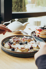 A man eats cheesecakes in a cafe for breakfast, a traditional Ukrainian dish.