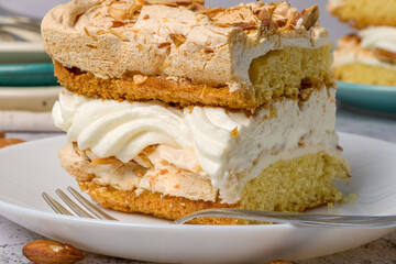 Norwegian cake. With meringue, whipped cream and almonds. Light background.