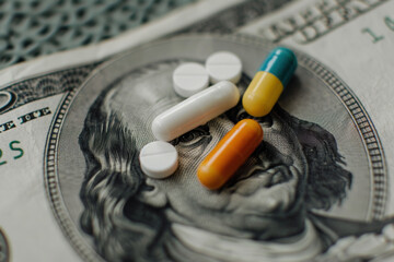 Medical costs, treatment costs, private medical insurance. Colorful medicine capsules and pills on US dollar bill. Top view