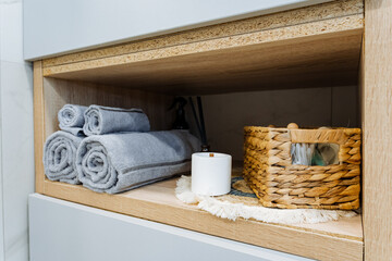 Discover a stylish bathroom storage solution featuring beautifully rolled towels alongside a decorative basket to enhance your space