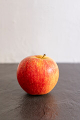 Red apple on a black background with a white wall in the background