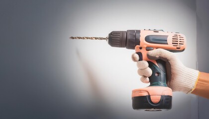 Hand holding a cordless drill with a bit against a wall. - Powered by Adobe