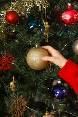 Decorating the tree, child hanging an ornament on the Christmas tree.