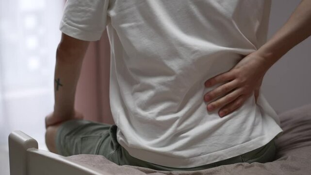 A person has lower back pain.
Back pain.
A man sits on a bed and cannot get up due to severe back pain.
A guy with an injured back.
Back, pain, injury, treatment