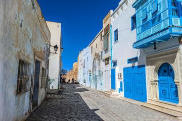 One of the streets of the old Tunisian cities, where the distinctive Tunisian Arab architecture is evident, with the beautiful colours of its doors and windows and its narrow streets.