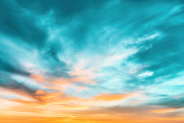 Fototapeta premium Vibrant sky with a mix of blue and orange hues at sunset, featuring dynamic and wispy clouds creating an energetic and colorful atmosphere.