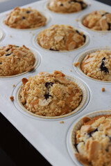 Process of making home-made blueberry muffins with almond crumble and lavander from scratch, side view close-up in a baking tray