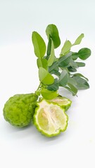 The kaffir lime or bergamot fruit with two half of fruit and green leaf on white background with copy space
