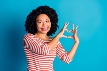 Photo of nice young woman show heart empty space wear striped shirt isolated on blue color background