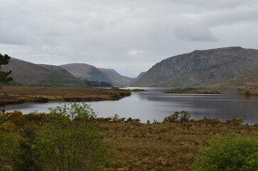 A lake by the shore with mountains in the background on a cloudy day in Ireland