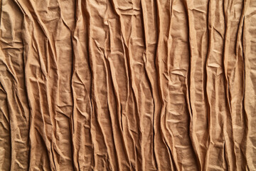 Fototapeta premium Close-up of tan-colored wrinkled fabric texture creating vertical lines and folds