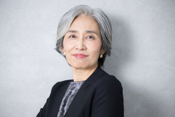 スーツを着たグレイヘアのシニア女性の美容やビューティーのイメージ　カメラ目線