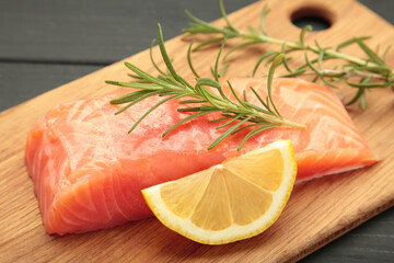 Red fish. Raw salmon fillet with rosemary and lemon on cutting board