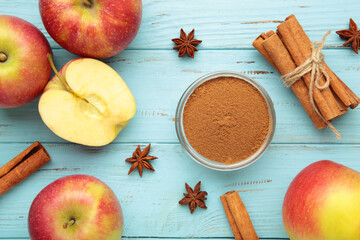 Red apple, apple slice, cinnamon sticks and star anise on blue wooden background.